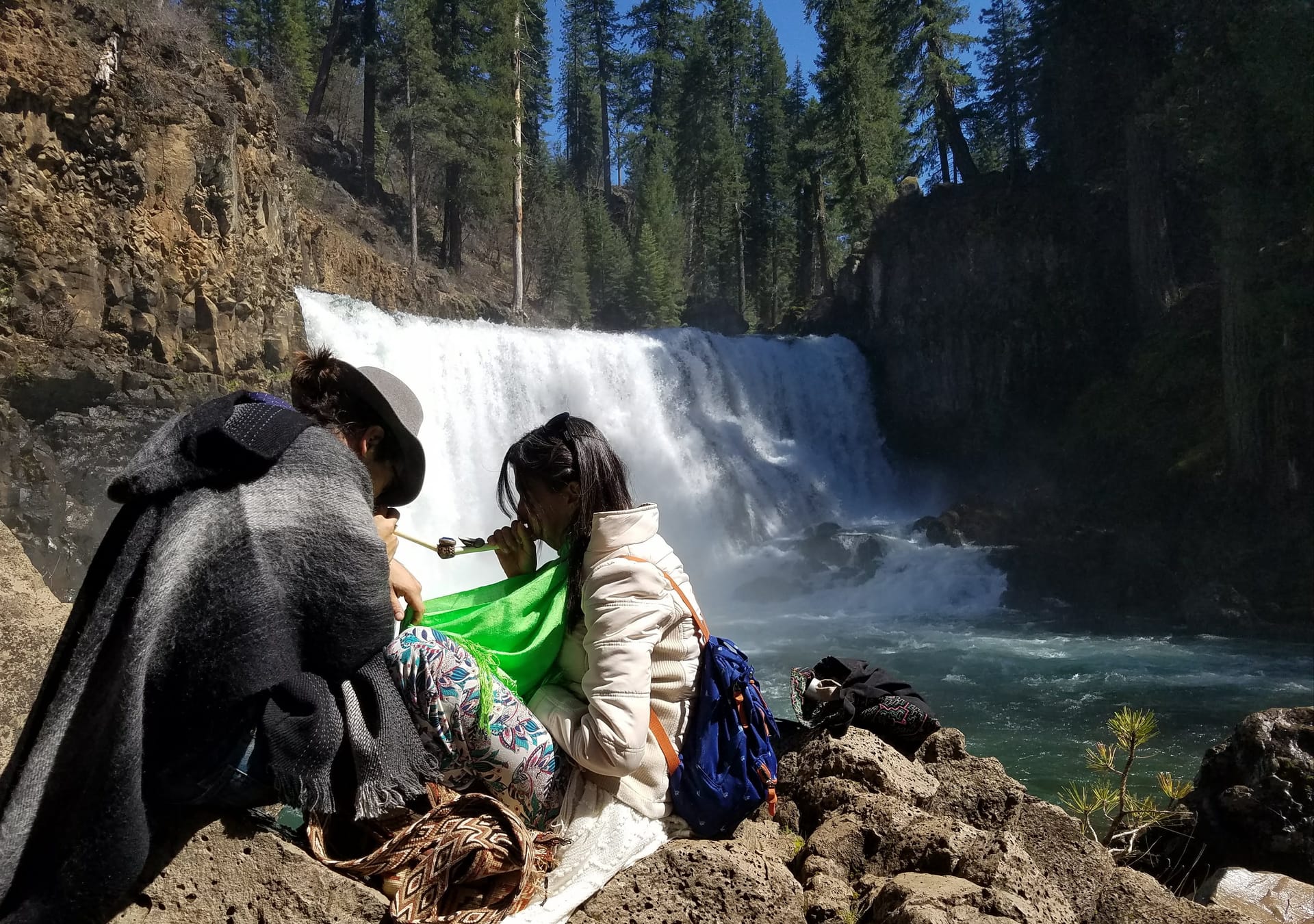 Hikers at a waterfall in a lush forest landscape