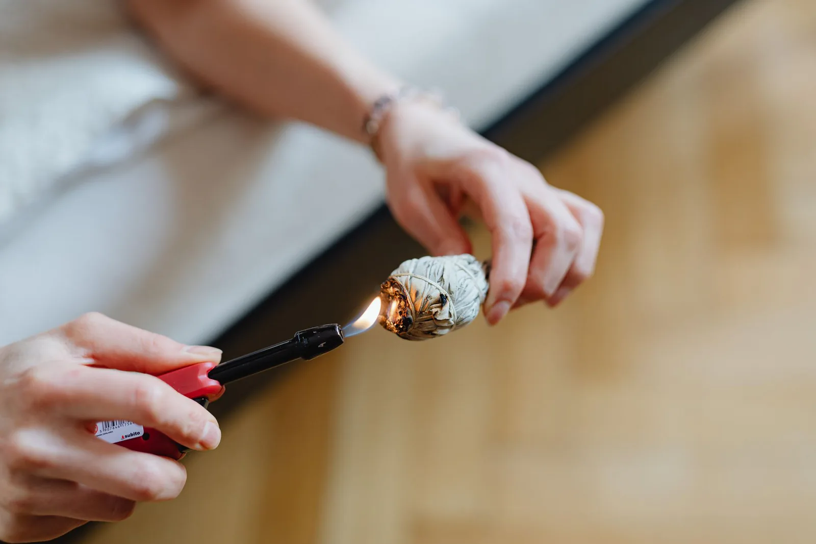 Hands lighting a sage smudge stick for ceremonial preparation